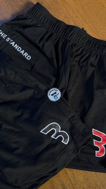 Acercamiento de los mesh shorts de la merch de CBum en color negro, uno con una B del logo en color blanco y rojo y otro con una en color blanco y negro