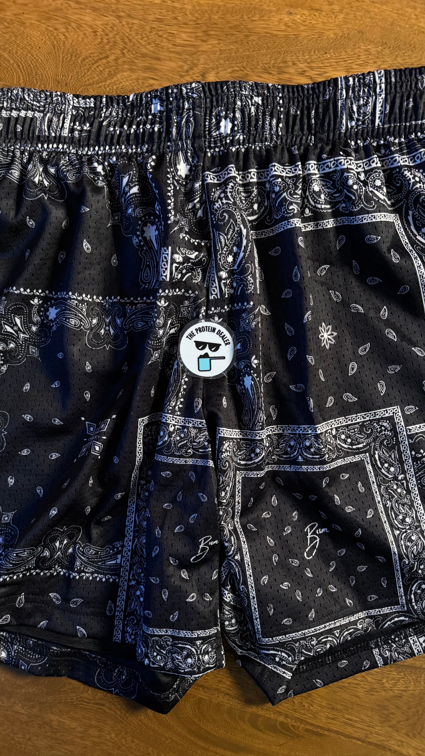 mesh shorts de la merch de CBUM en color blanco y negro con un patrón "paisley" o como bandana