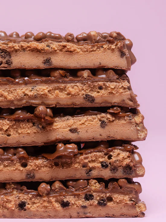 Acercamiento barrita Barebell sabor cookies and caramel mostrando detalles del relleno, cobertura y adiciones crocantes