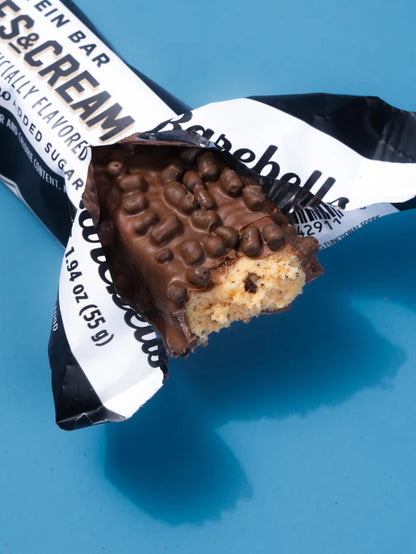 Barrita Barebell sabor cookies and cream abierta mostrando detalles del relleno, cobertura y adiciones crocantes