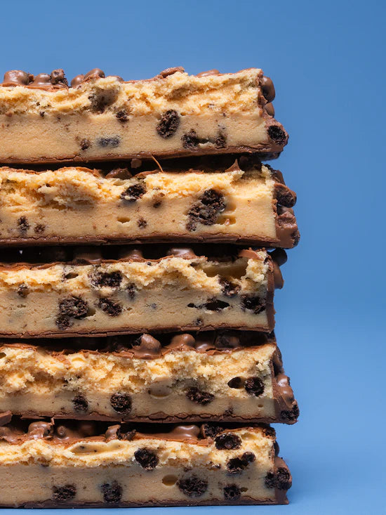 Acercamiento de Barrita Barebell sabor cookies and cream mostrando detalles del relleno, cobertura y adiciones crocantes
