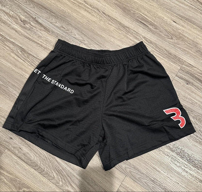 mesh shorts de la merch de CBUM en color negro, con una B de su logo en blanco y rojo y la frase "set the standard" en blanco